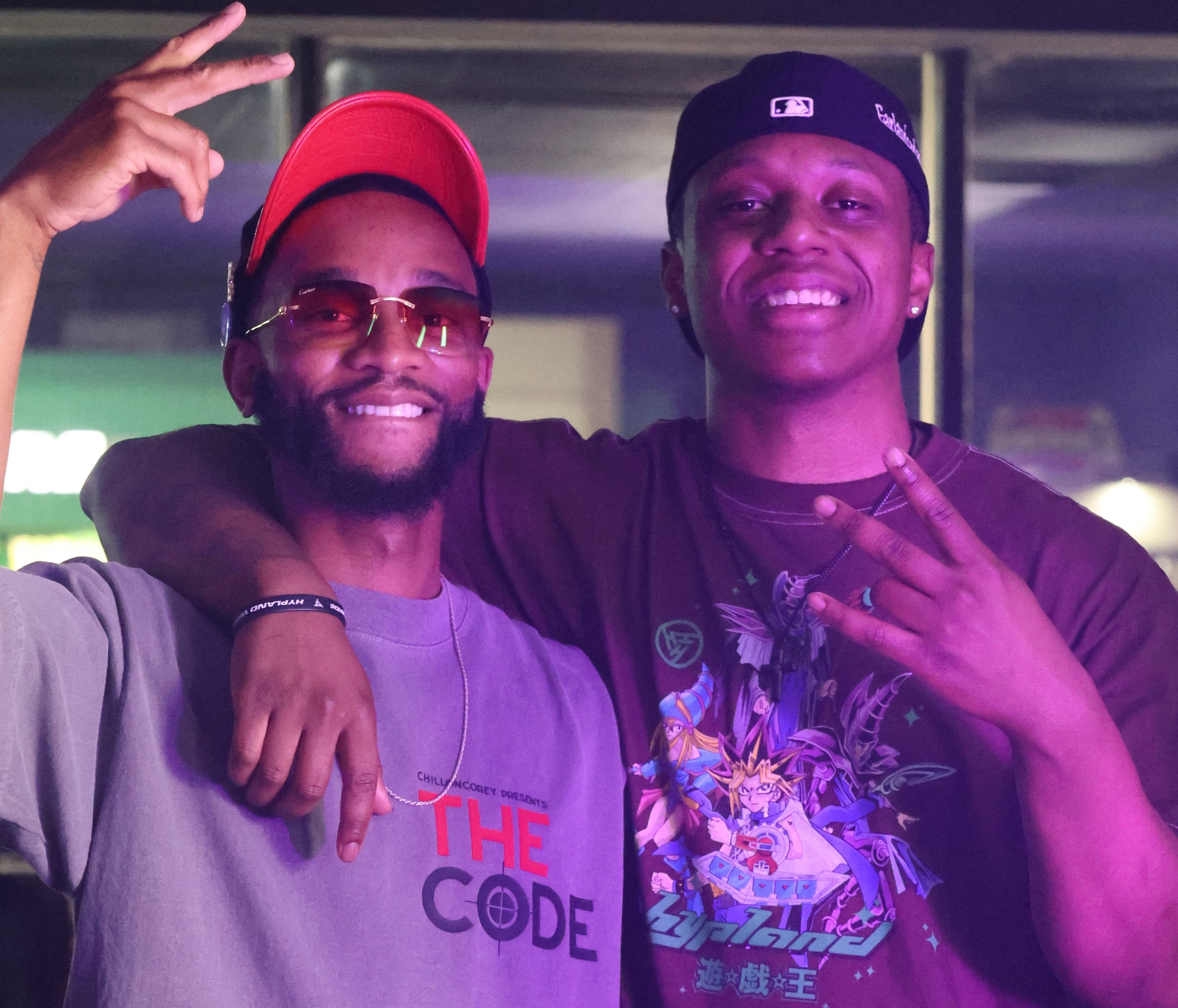 Two people standing close together with one wearing a 'The Code' shirt and the other in a colorful shirt.